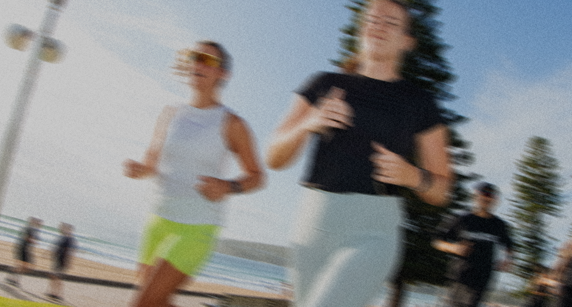 Two people running on a beach with a blurred background
