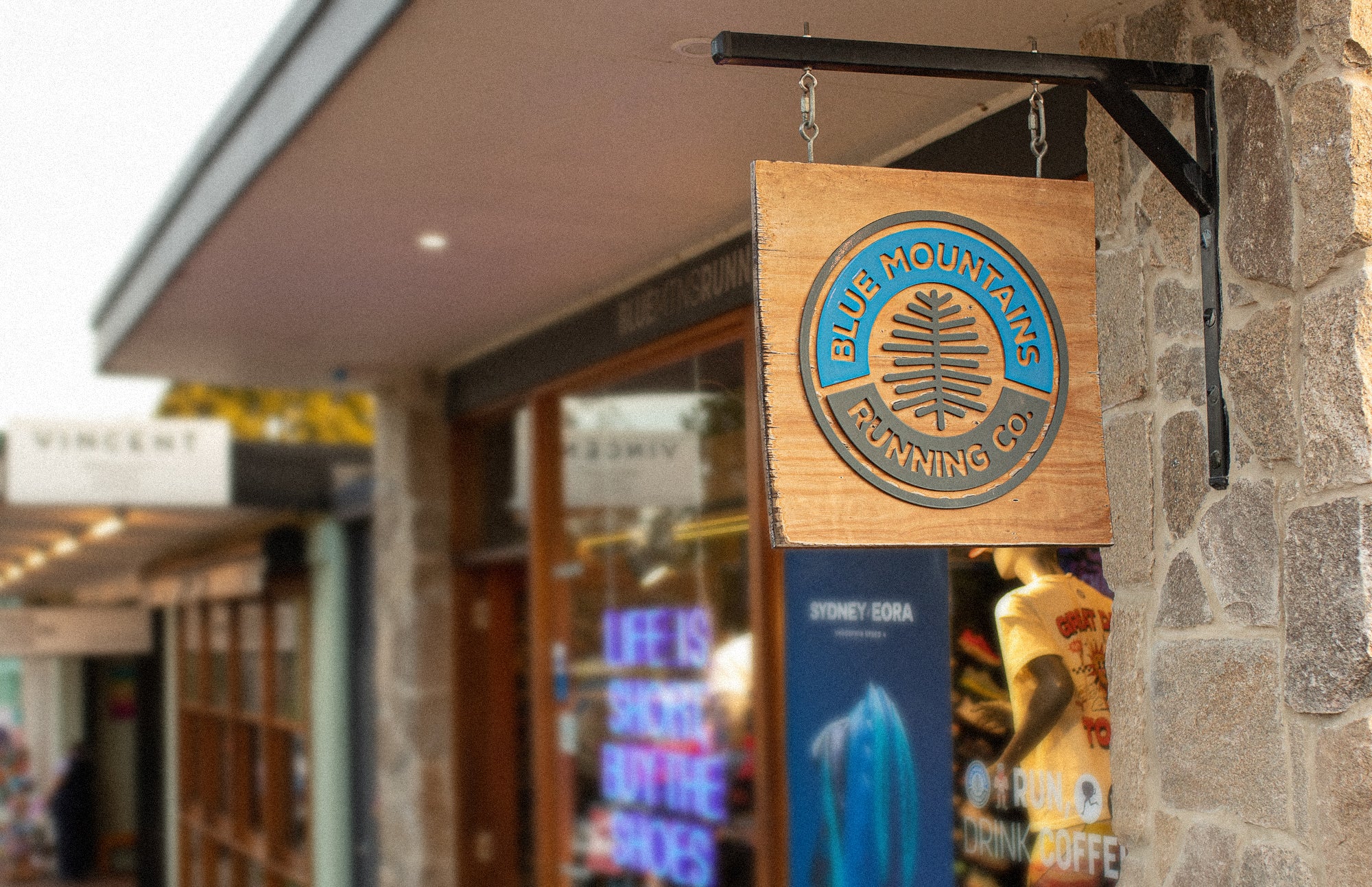 Wooden sign with 'Blue Mountains Penning Co' logo hanging outside a store.