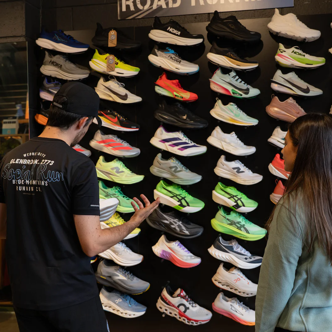 Two people examining a display of colorful running shoes in a store.